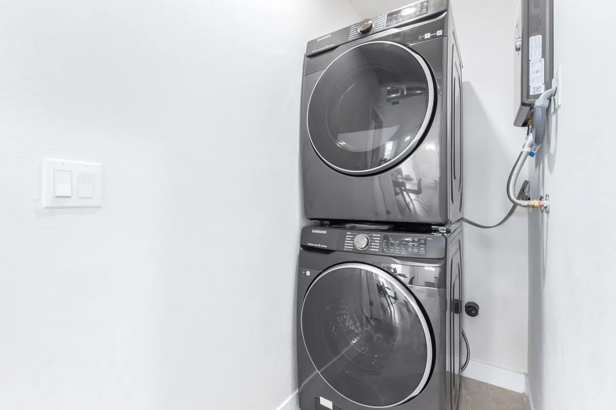 A functional laundry area featuring a stacked washer and dryer, optimized for efficient use of space. The zone appears tidy and practical, supporting longer stays and daily convenience.