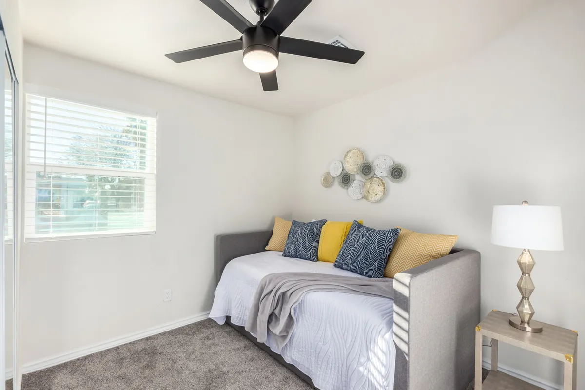 This interior scene highlights a daybed adorned with decorative pillows, soft lighting from a lamp, and artistic wall décor. The space feels tranquil and comfortable, perfect for reading, relaxing, or a quick nap between work sessions.