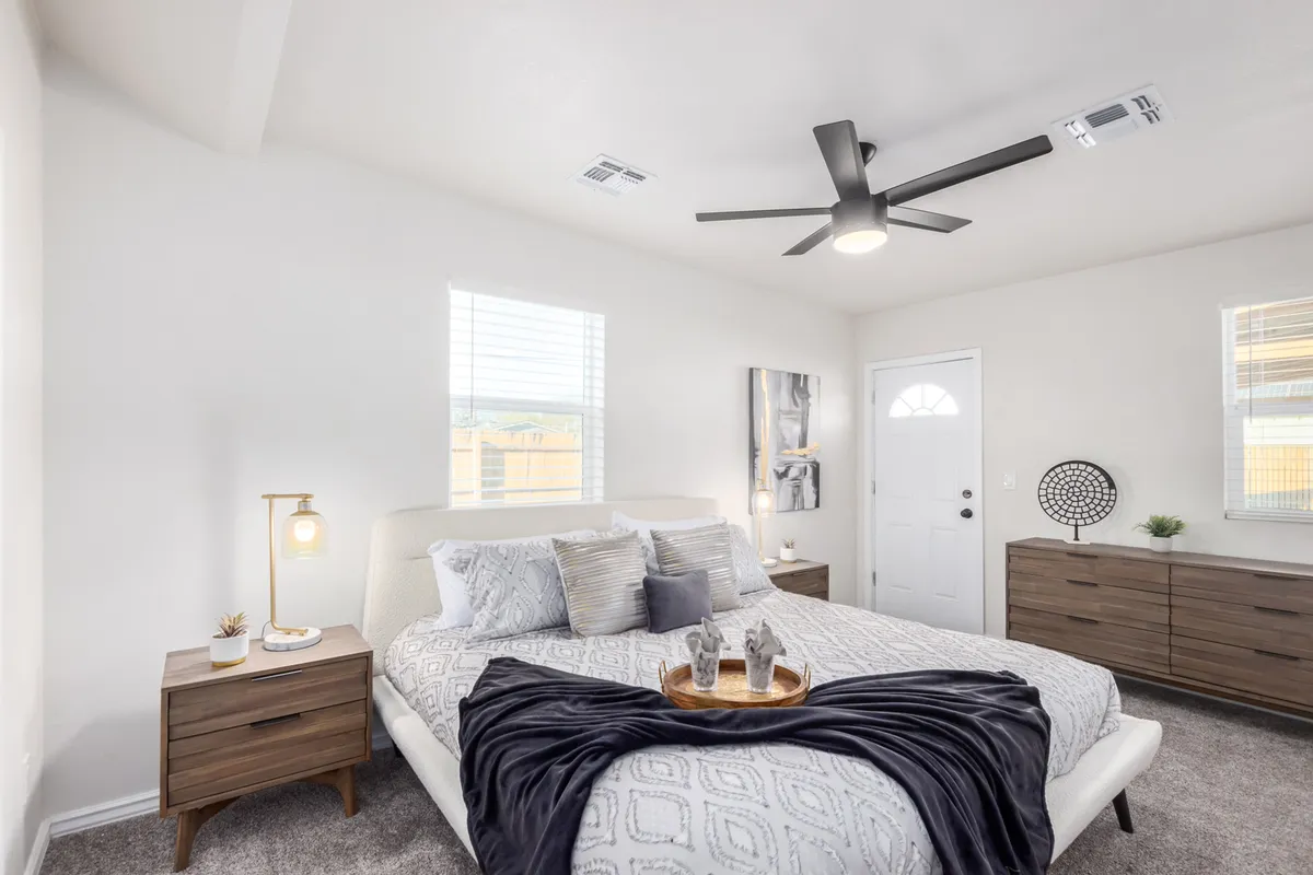 A serene bedroom featuring a daybed topped with decorative pillows, a nightstand with a glowing lamp, tasteful wall art, and a window allowing natural light to fill the space. The layout is versatile, suited for children, friends, or coworkers.