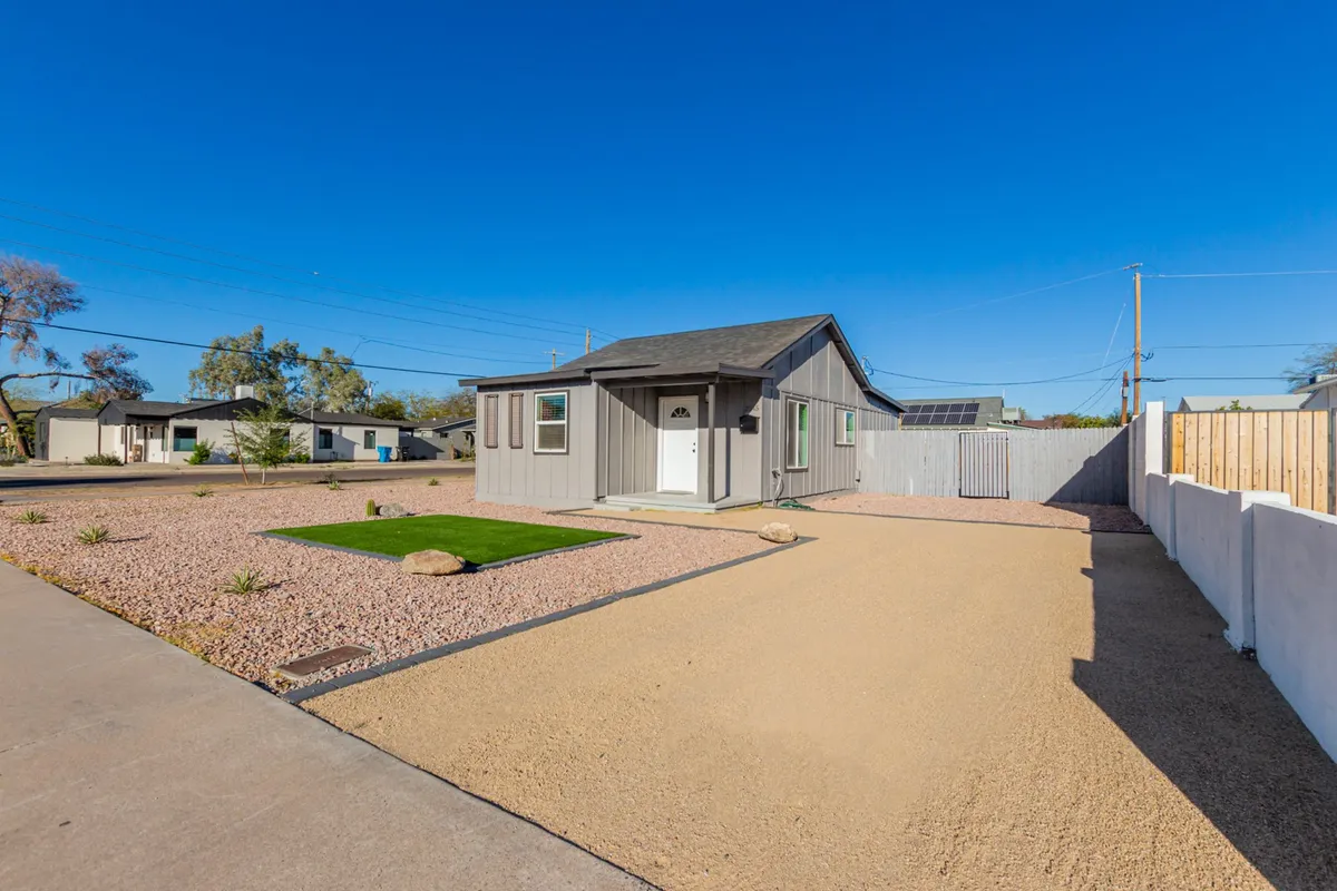 This exterior image captures the full view of the house set against a green lawn and gravel driveway, with hints of sunset lighting. The setting feels approachable, safe, and ideal for winding down after a busy shift. The relaxed mood echoes the promise of quiet mornings or evenings, reinforcing the urban convenience and comfort themes.