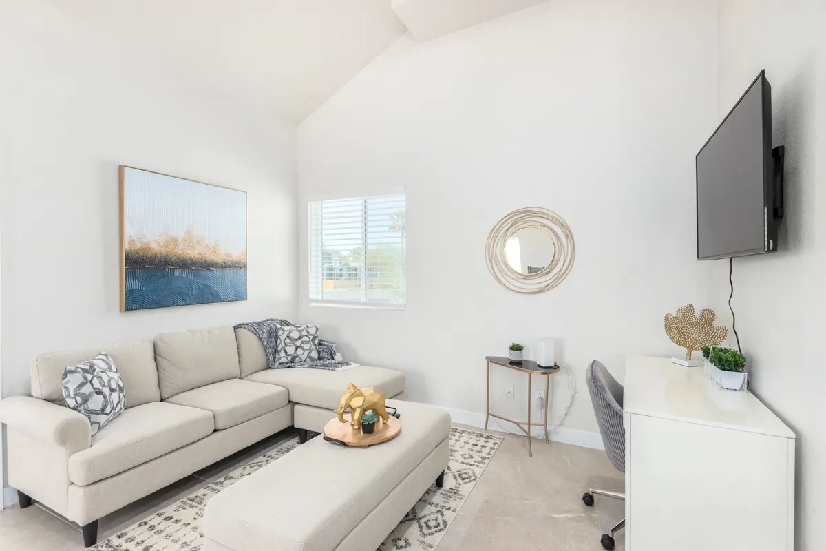 Another angle of the primary living space, this image features a comfortable sofa, artwork, TV, decorative mirror, and a coffee table. The serene mood and thoughtful decor reinforce the blend of modern comfort and classic charm, inviting relaxation and social moments.